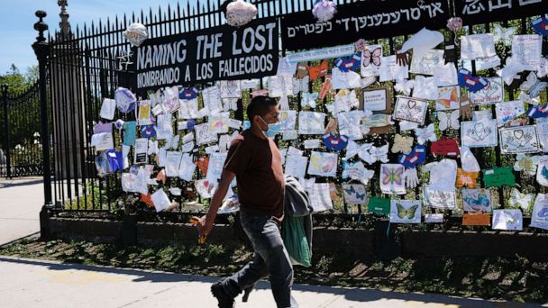 PHOTO: A man walks by a memorial for those who have died from the novel coronavirus outside Green-Wood Cemetery on May 27, 2020, in the Brooklyn borough of New York.