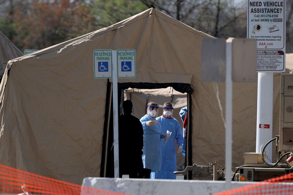 PHOTO: Healthcare professionals prepare to screen people for the coronavirus at a testing site erected by the Maryland National Guard in a parking lot at FedEx Field, March 30, 2020, in Landover, Md.