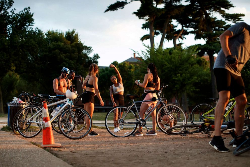PHOTO: A group of cyclists takes a break on the sidewalk on the National Mall in Washington, D.C., July 19, 2020.