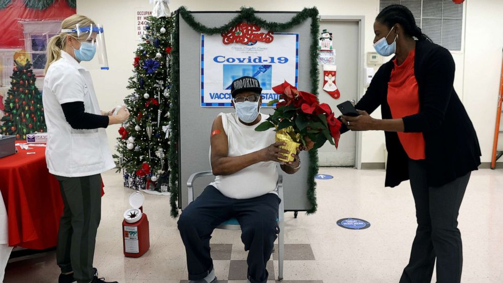 PHOTO: A patient at Crown Heights Center for Nursing and Rehabilitation is given a plant to congratulate him after he received the coronavirus disease vaccine from Walgreens Pharmacist Annette Marshall, in the Brooklyn borough of New York, Dec. 22, 2020.