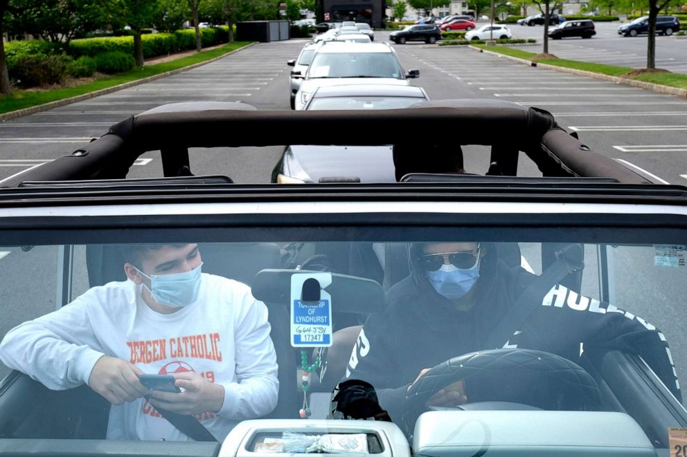 PHOTO: Adam Abdelouahad, right, and Brandon Esper wait in line, in a car, to pick up an order from Dick's Sporting Goods in Paramus, N.J., May 18, 2020.