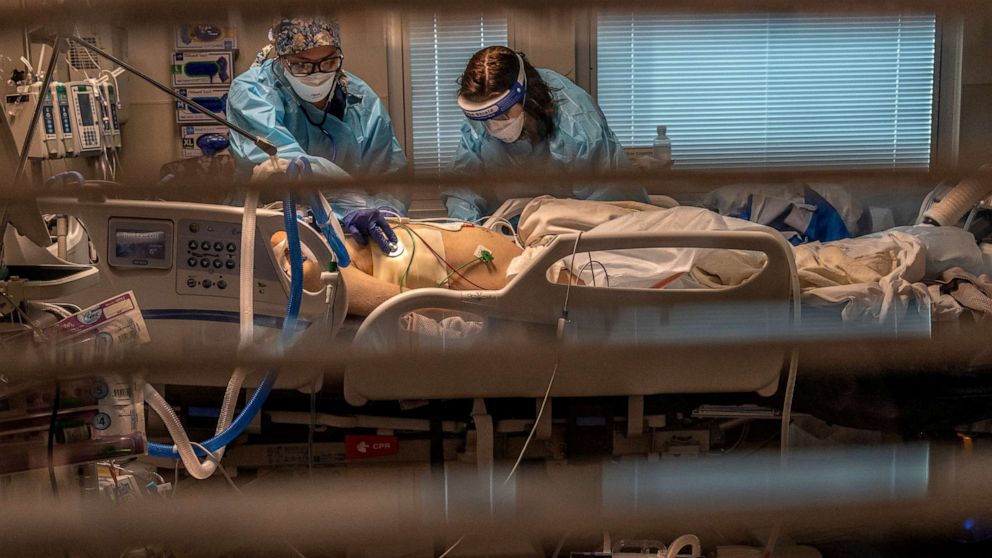 PHOTO: Registered Nurse Carina Klescewski and Phlebotomist lab assistant Jennifer Cukati care for a COVID-19 patient inside the Sutter Roseville Medical Center ICU in Roseville, Calif., on Dec. 22, 2020.