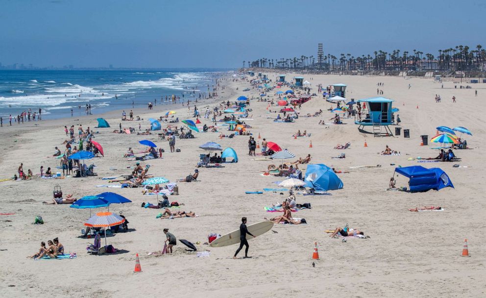 PHOTO: Some beach-goers wear masks while others don't outside while recreating at the pier on Monday, July 20, 2020, in Huntington Beach, Calif.