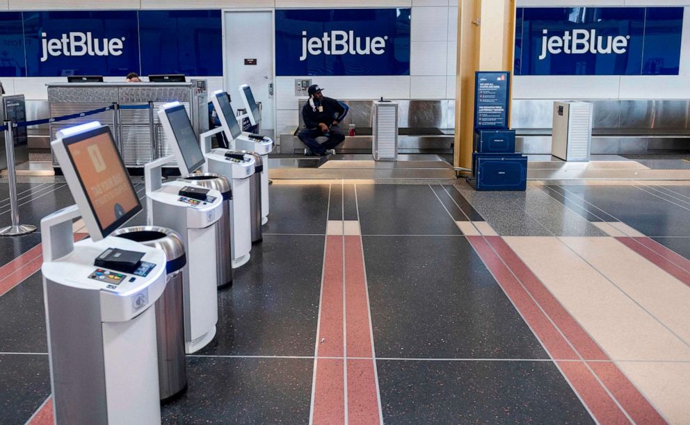 PHOTO: A JetBlue employee waits for passengers at an empty check-in counter at Ronald Reagan Washington National Airport in Arlington, Va., on May 12, 2020.
