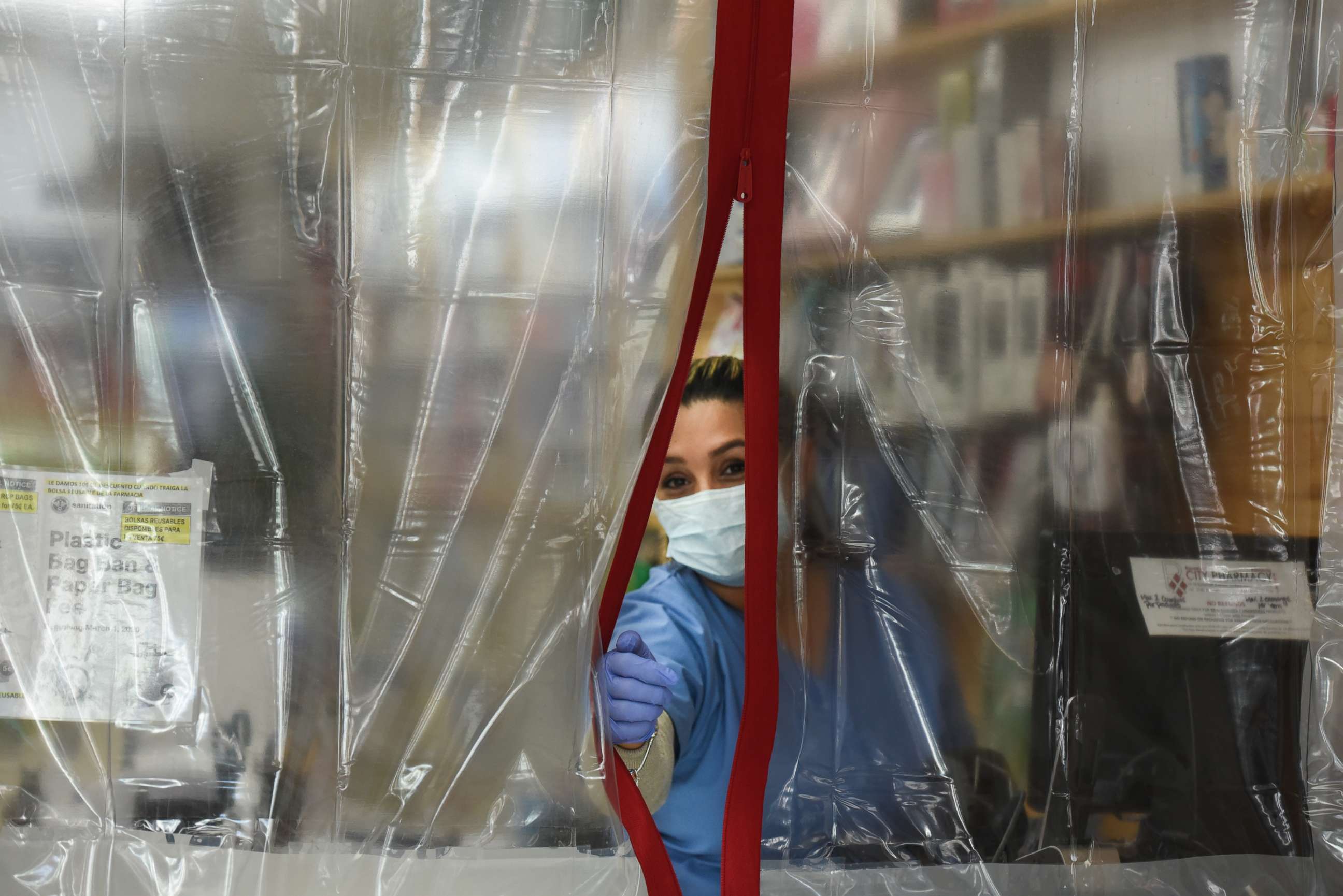 PHOTO: A pharmacist works behind plastic sheeting while wearing personal protective equipment in the Elmhurst neighborhood on April 1, 2020, in New York.