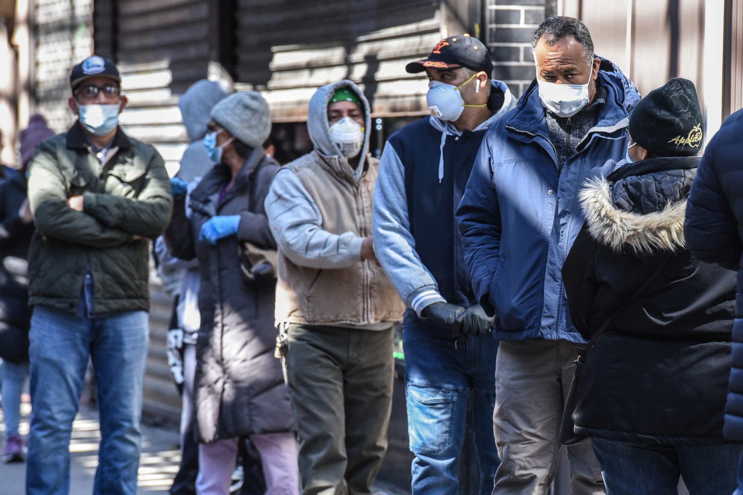PHOTO: People stand in line while wearing face masks in the Elmhurst neighborhood on April 1, 2020, in New York.