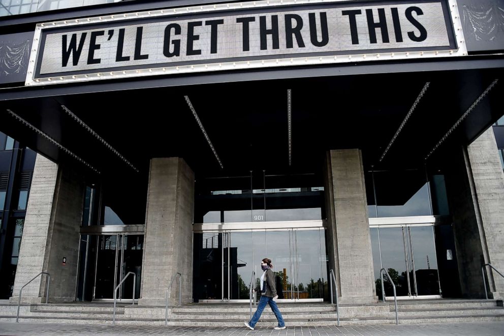 PHOTO: A woman wearing a face mask walks past a sign in front of The Anthem, a popular live music venue, on April 29, 2020, in Washington, D.C.