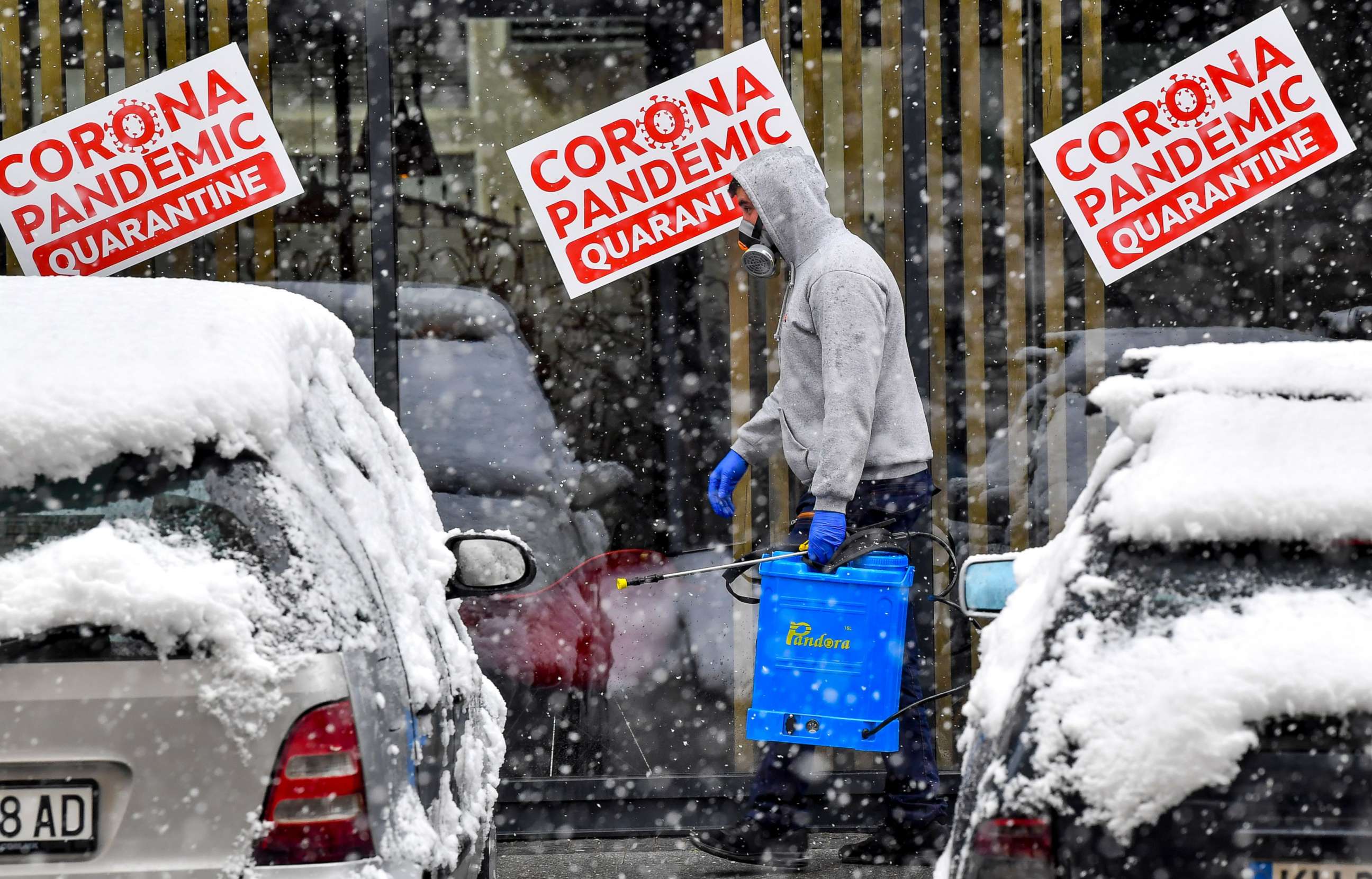 PHOTO: A man with protective mask carries disinfectant near the hotel which serves as a state quarantine for people that arrived from abroad during the snowfall in the center of Skopje, Republic of North Macedonia, April 1, 2020.