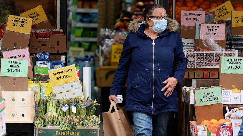 PHOTO: A customer wearing a facemask leaves with groceries from a local supermarket on March 20, 2020, in the Brooklyn borough of New York.