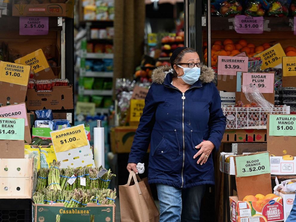 PHOTO: A customer wearing a facemask leaves with groceries from a local supermarket on March 20, 2020, in the Brooklyn borough of New York.