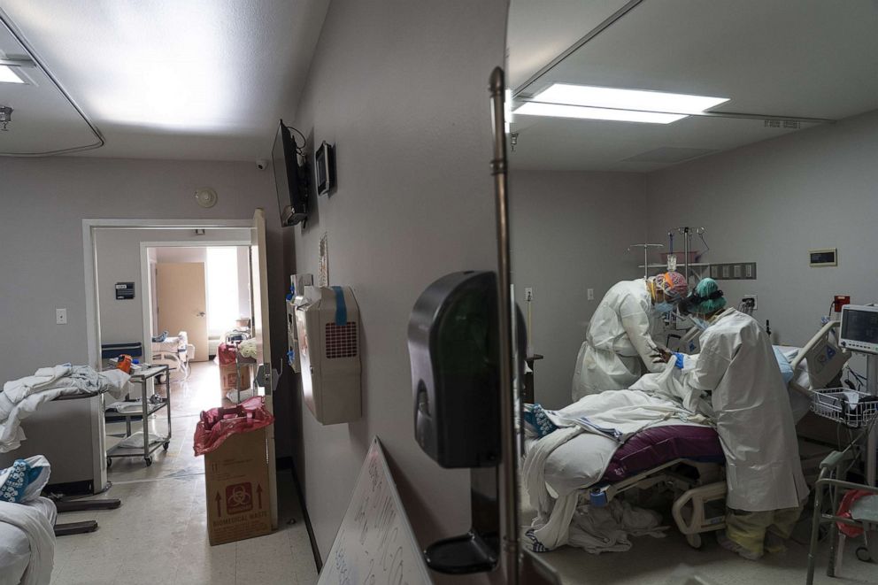 PHOTO: Medical staff wearing full PPE change a patient's clothes in the COVID-19 intensive care unit at the United Memorial Medical Center on June 30, 2020, in Houston.