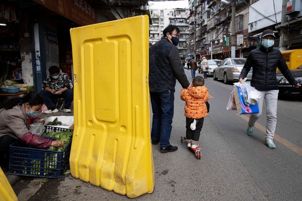 PHOTO: Vendors prepare vegetables behind barriers surrounding a neighborhood in Wuhan in central China's Wuhan province on April 1, 2020.