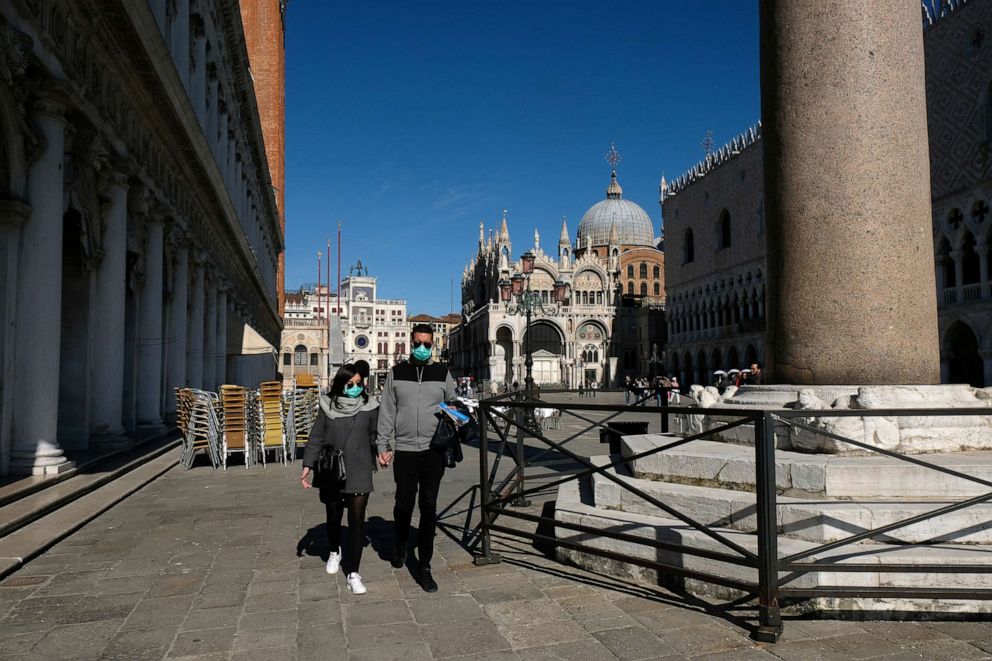 PHOTO: Tourists wearing protective masks walk through an empty Saint Mark's Square in Venice as Italy battles a coronavirus outbreak, Venice, Italy, Feb. 27, 2020.