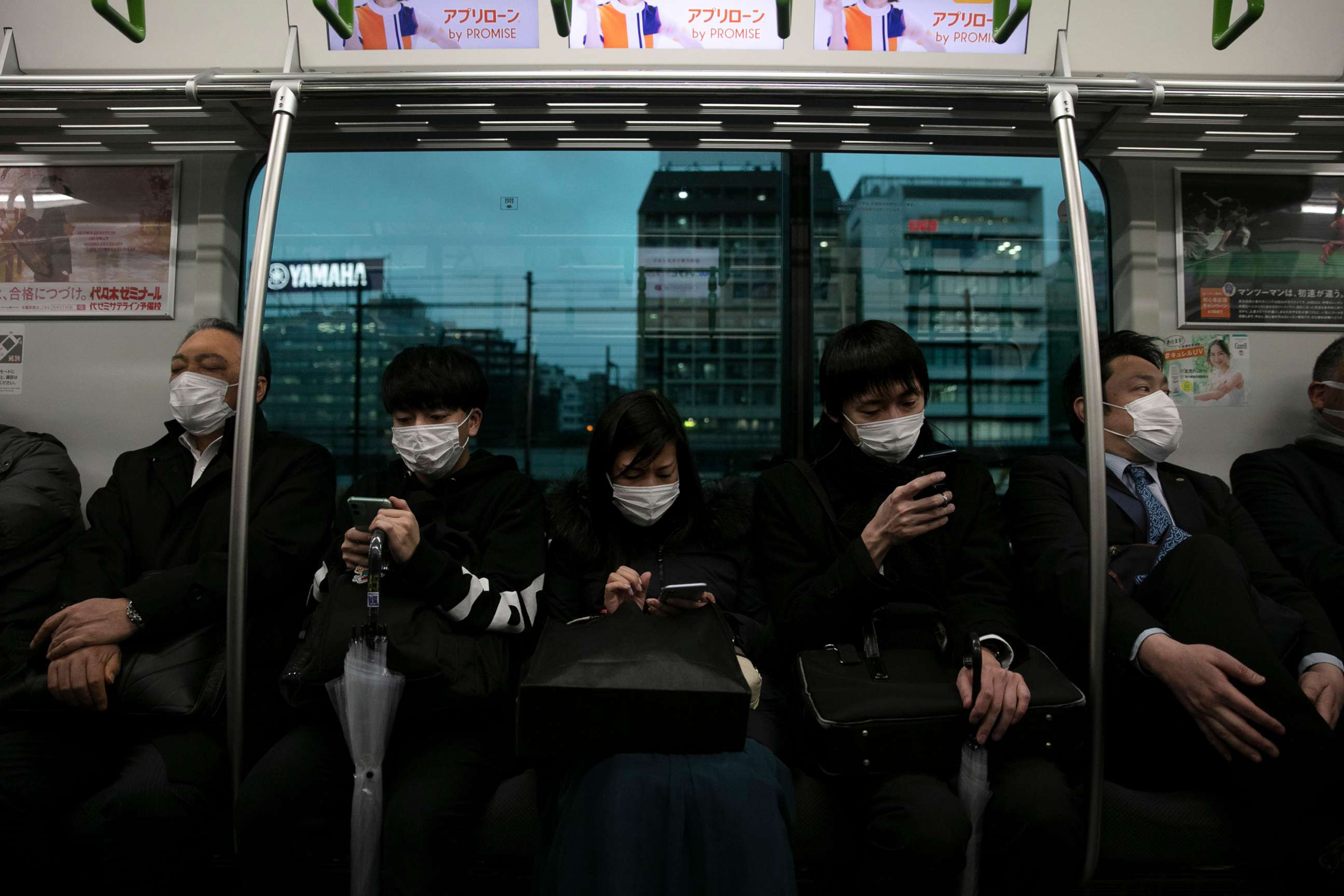 PHOTO: Commuters wearing masks sit on a train in Tokyo, March 2, 2020.