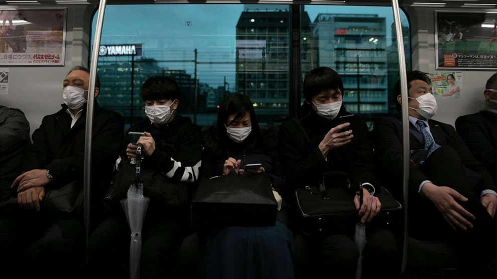 PHOTO: Commuters wearing masks sit on a train in Tokyo, March 2, 2020.