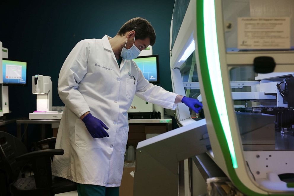 PHOTO: Lab Technician Carter Tavaglione loads at Janus G3 automated workstation with coronavirus test samples at Advagenix, a molecular diagnostics laboratory, Aug. 5, 2020, in Rockville, Md.