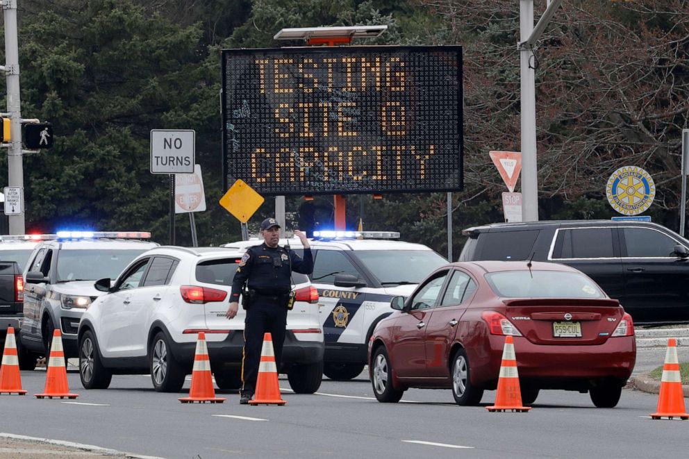 PHOTO: A police officer waves traffic past the entrance to a drive-through COVID-19 testing center after it reached capacity in Paramus, N.J., Friday, March 20, 2020.