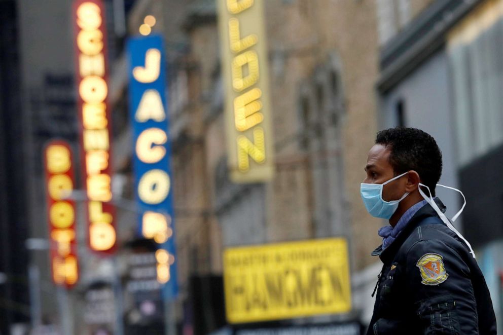 PHOTO: A man in a surgical mask walks through Manhattan's Broadway Theatre district after Broadway shows announced they will cancel performances due to the coronavirus outbreak in New York, March 12, 2020.