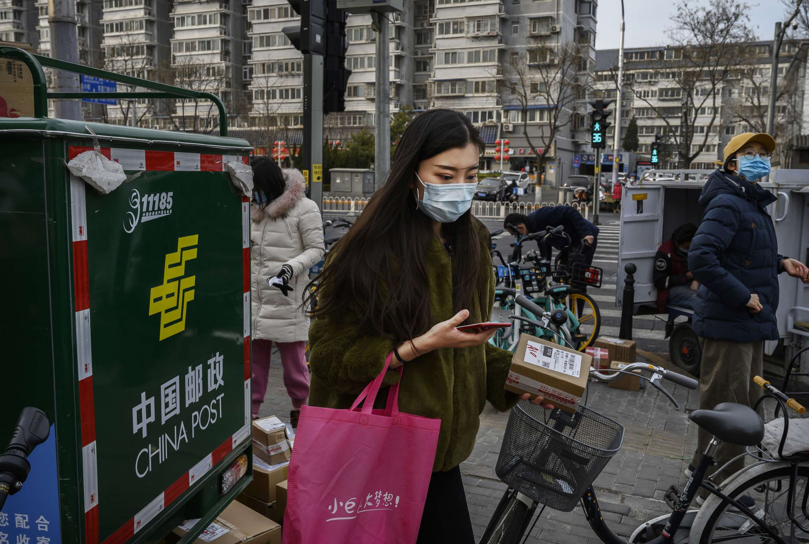 PHOTO: A woman wears a protective mask as she collects her parcels from couriers outside a residential compound, Feb. 26, 2020, in Beijing, China.