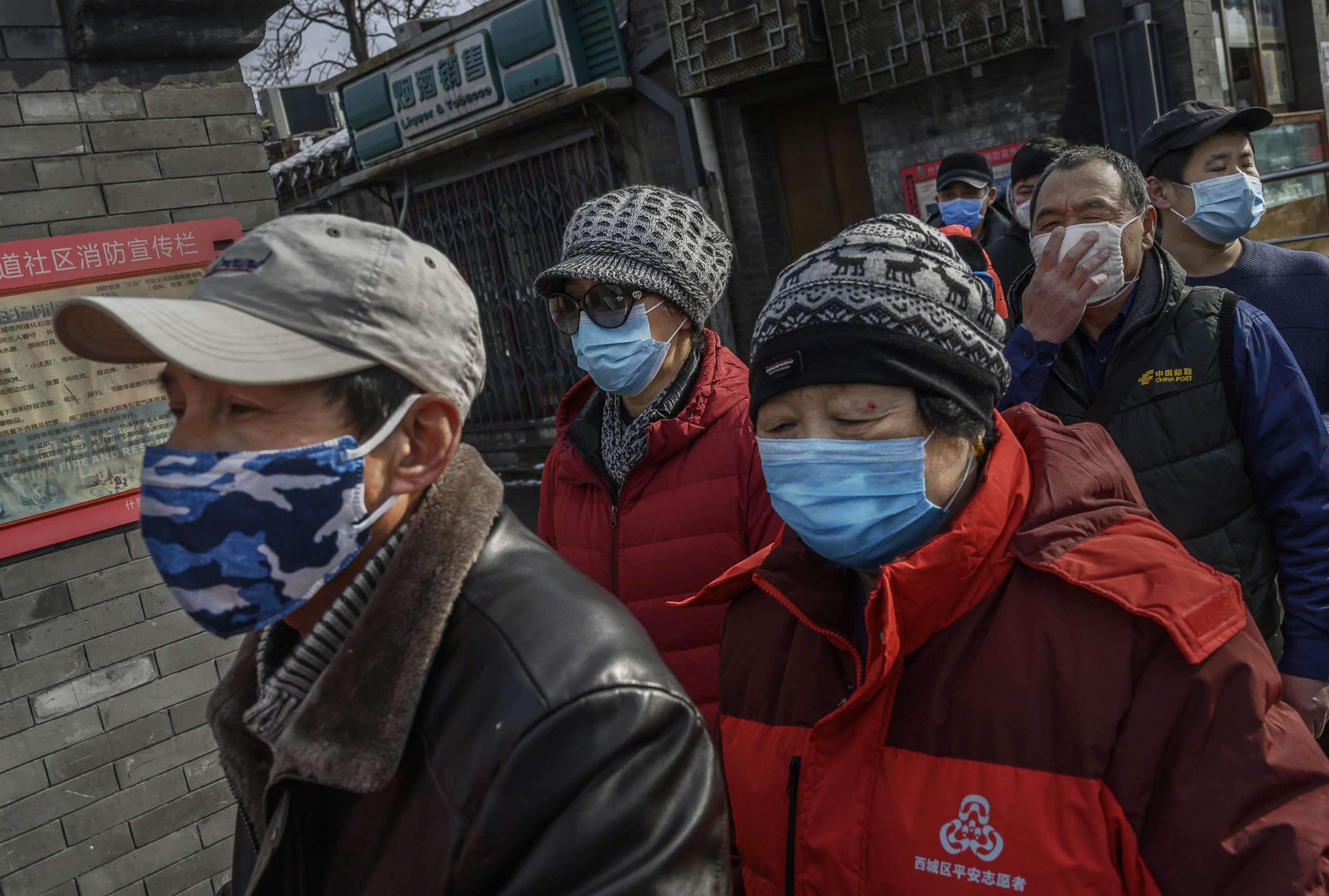PHOTO: Local Chinese residents wear protective masks as they wait in line to get a ticket to receive free masks and cleaner outside a pharmacy in Beijing, Feb. 8, 2020.