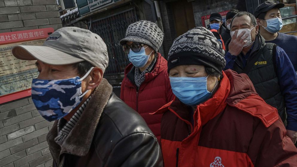 PHOTO: Local Chinese residents wear protective masks as they wait in line to get a ticket to receive free masks and cleaner outside a pharmacy in Beijing, Feb. 8, 2020.