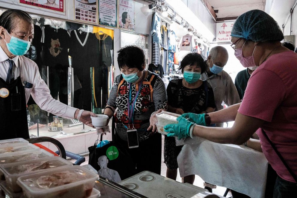 PHOTO: People wearing facemasks receive free meal boxes given out by Gingko House restaurant workers and volunteers in Hong Kong on March 27, 2020.