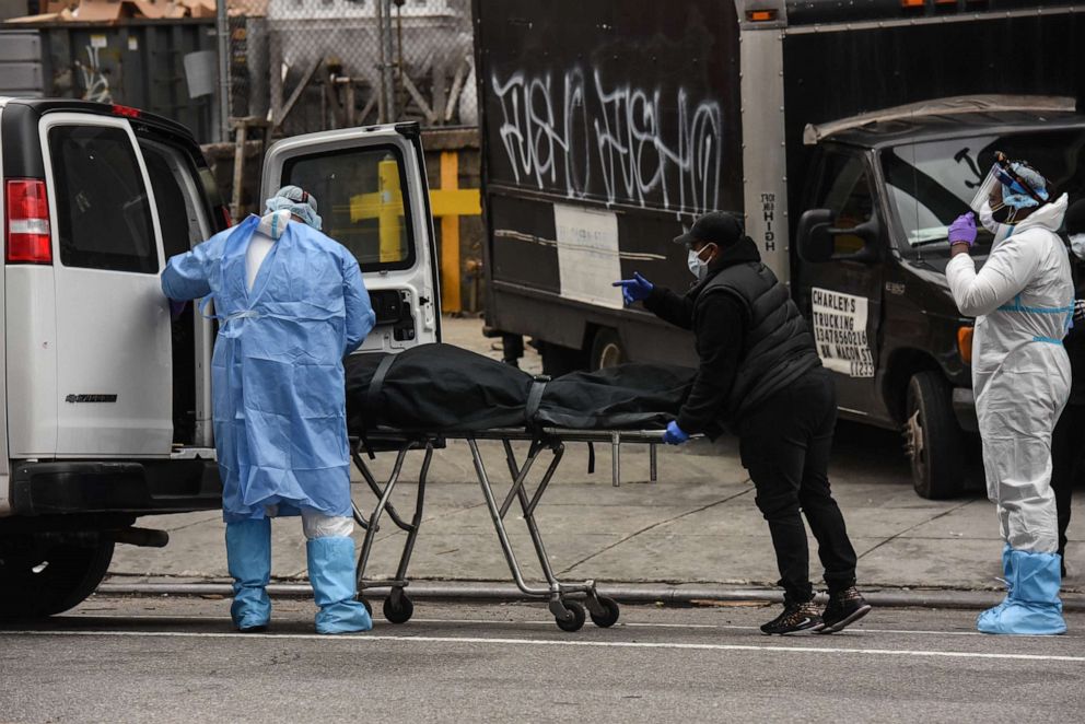 PHOTO: A funeral worker is assisted moving a deceased patient into a van at the Brooklyn Hospital Center on April 27, 2020, in New York.