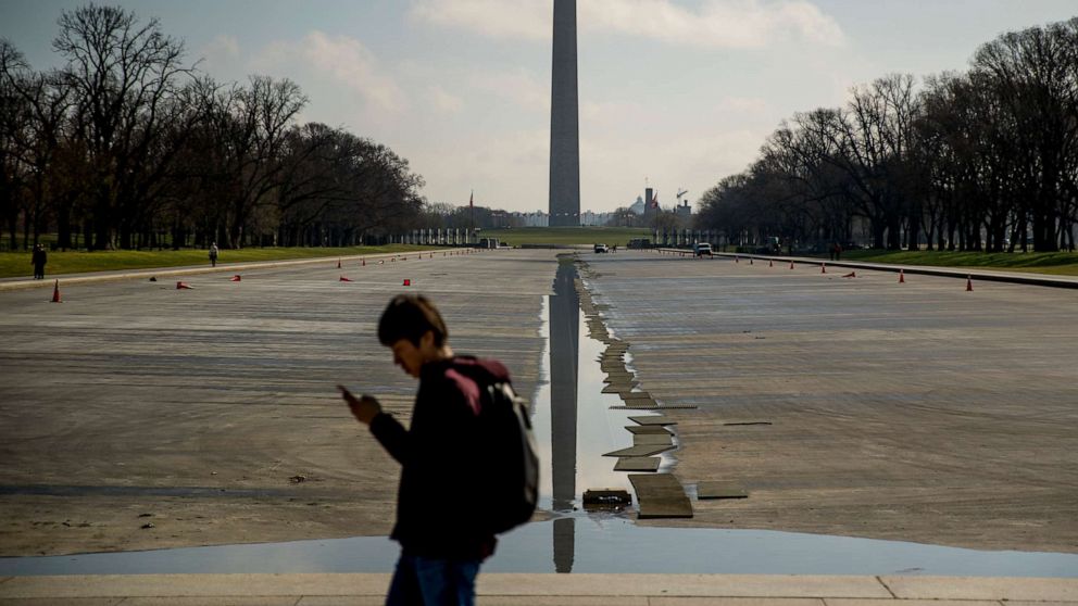 PHOTO: The Washington Monument is visible as a man walks along the drained Reflecting Pool on the National Mall, Friday, March 13, 2020, in Washington.