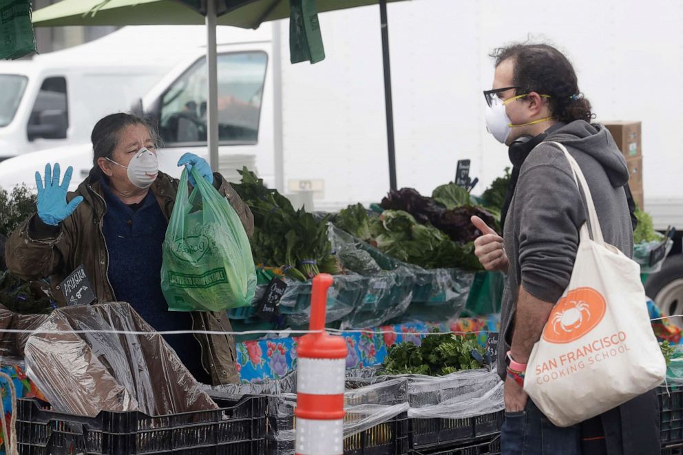 PHOTO: Annabelle Lenderink wears a mask while helping customer Justin Angel at the Star Route Farms stand at the Ferry Plaza Farmers Market in San Francisco, Saturday, March 28, 2020.
