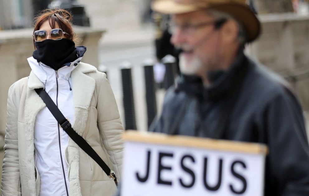 PHOTO: A woman covering her face walks down Whitehall, as a meeting takes place addressing the government's response to the coronavirus outbreak at Cabinet Office in London, March 12, 2020.