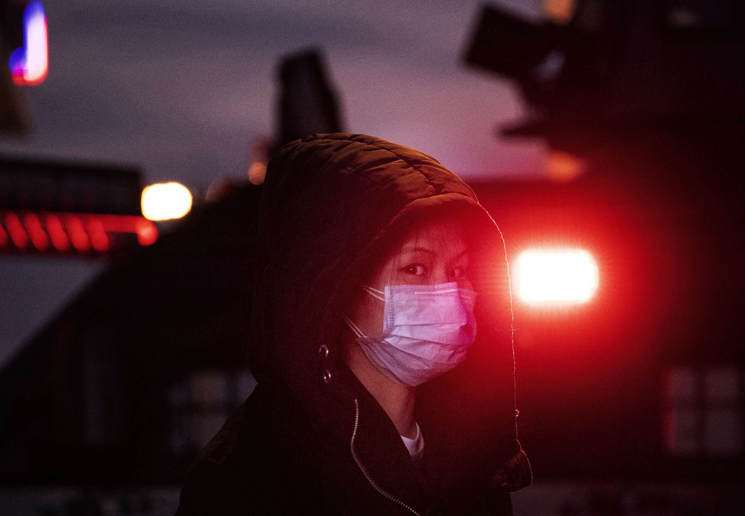 PHOTO: A Chinese woman wears a mask as she stands near the light of a police vehicle on regular duty at Beijing Railway station before the annual Spring Festival in Beijing, Jan. 21, 2020.