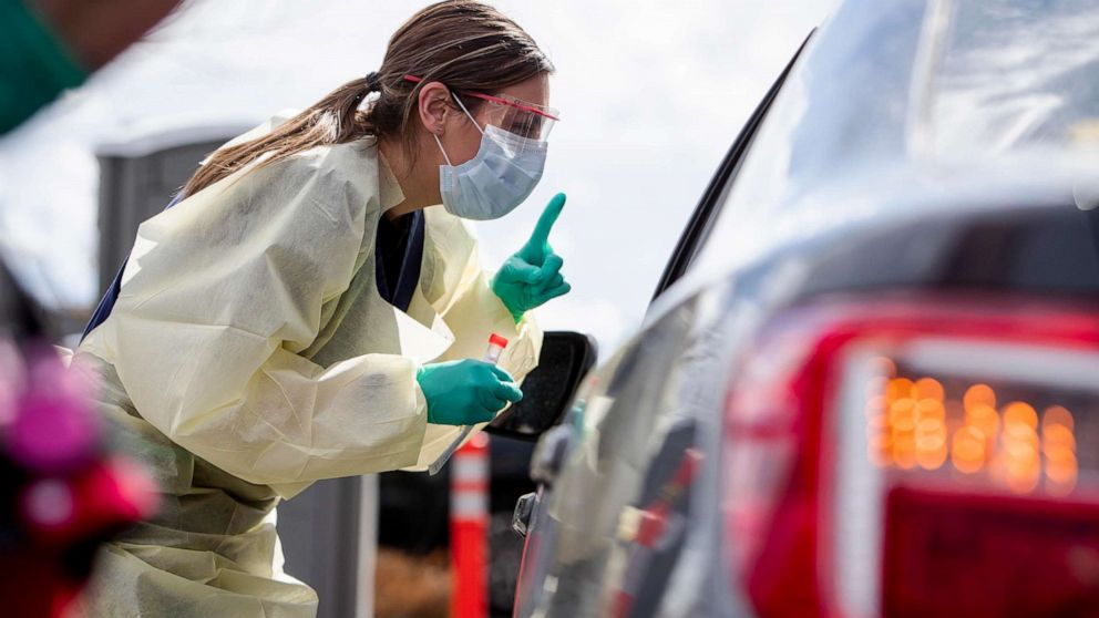 PHOTO: Ashley Layton, an LPN at St. Luke's Meridian Medical Center, communicates with a person exhibiting symptoms before taking swab sample at a special outdoor drive-thru screening station for coronavirus COVID-19, March 17, 2020, in Meridian, Idaho.