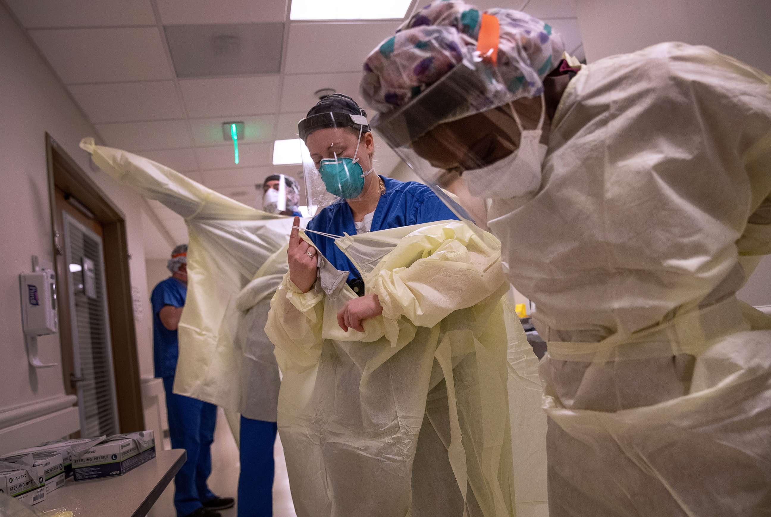 PHOTO: Medical workers don personal protective equipment before entering the room of a patient with COVID-19 in a Stamford Hospital intensive care unit, on April 24, 2020, in Stamford, Conn.