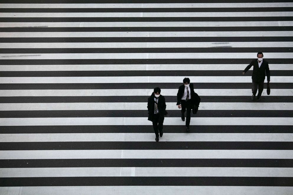 PHOTO: Commuters wearing masks walk across a pedestrian crosswalk, Feb. 26, 2020, in Tokyo.