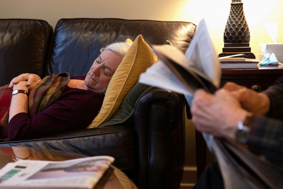 PHOTO: Penny Parkin, 69, who was exposed to COVID-19 on March 23, 2020, takes her daily afternoon nap while her husband, John Parkin, 85, reads the newspaper, in Doylestown, Pa., March 17, 2021.