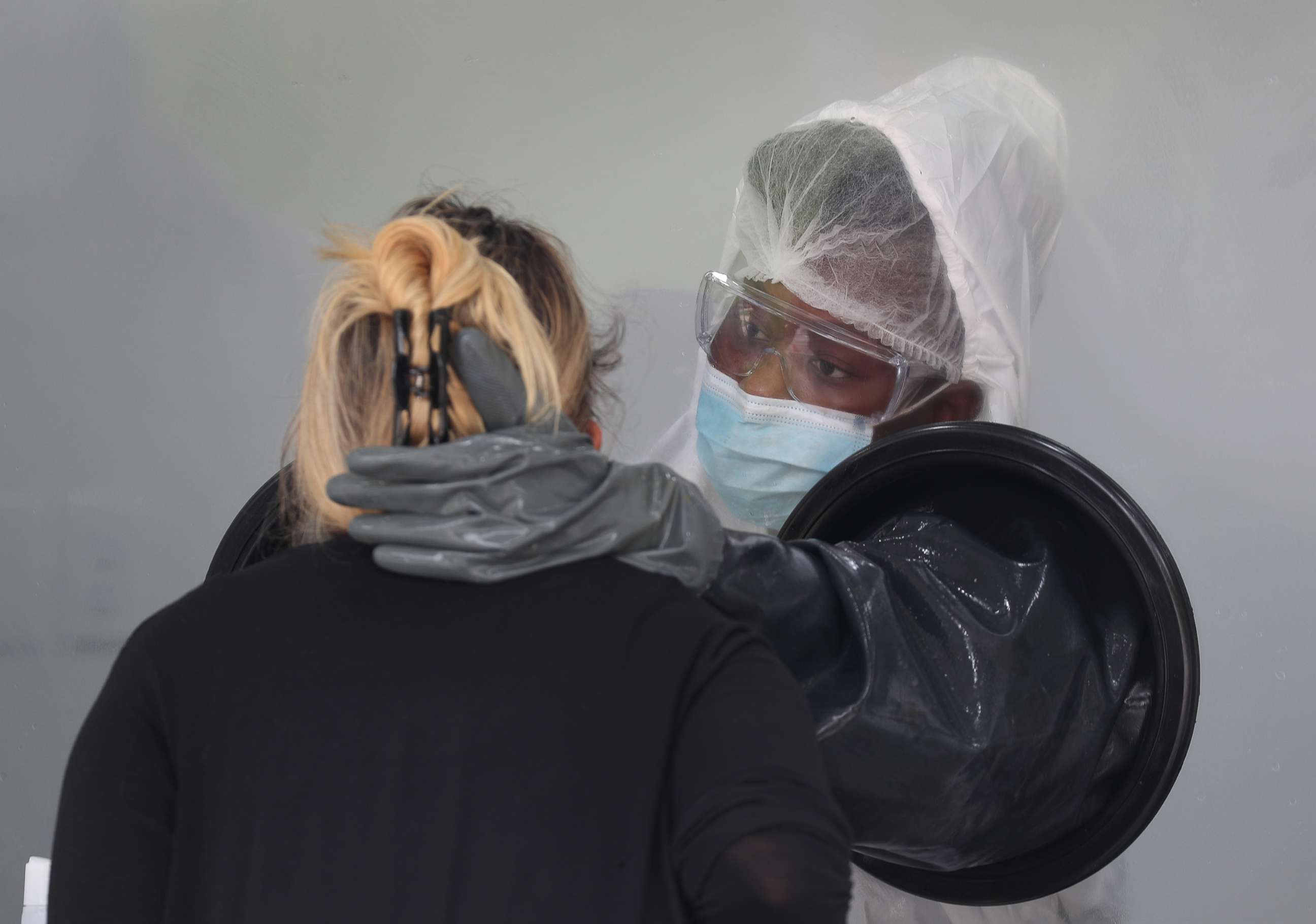 PHOTO: A nurse swabs the nose of a person through a glass pane in a mobile COVID-19 testing truck on July 17, 2020, in Miami Beach, Fla.