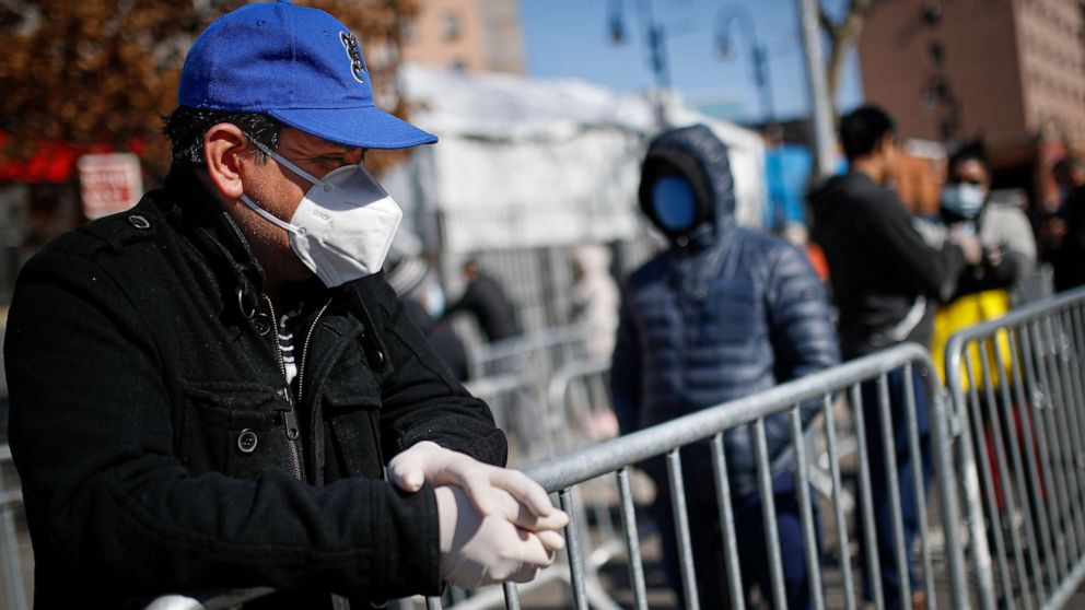 PHOTO: A patient wears a protective mask and gloves while waiting for COVID-19 testing outside Elmhurst Hospital Center, March 27, 2020, in New York.