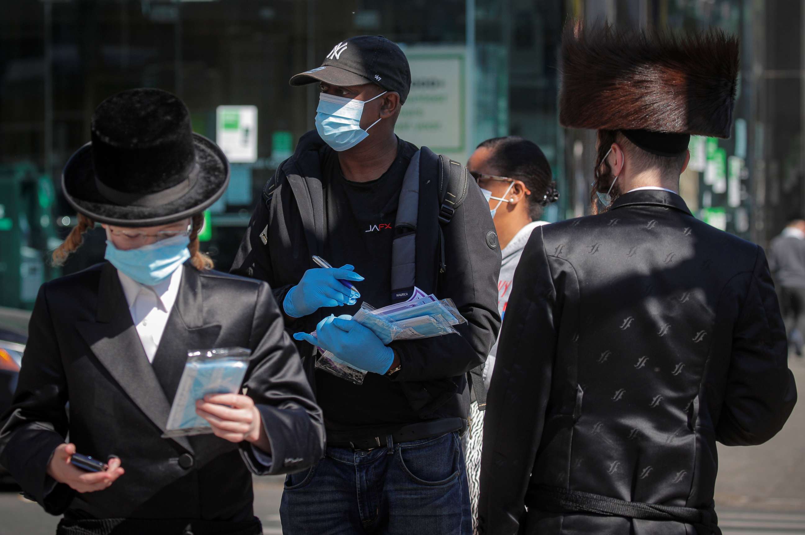 PHOTO: A member of New York City Test and Trace Corp. hands out masks to Ultra-Orthodox Jewish men during the outbreak of coronavirus disease in the Brooklyn borough of New York, Oct. 9, 2020.