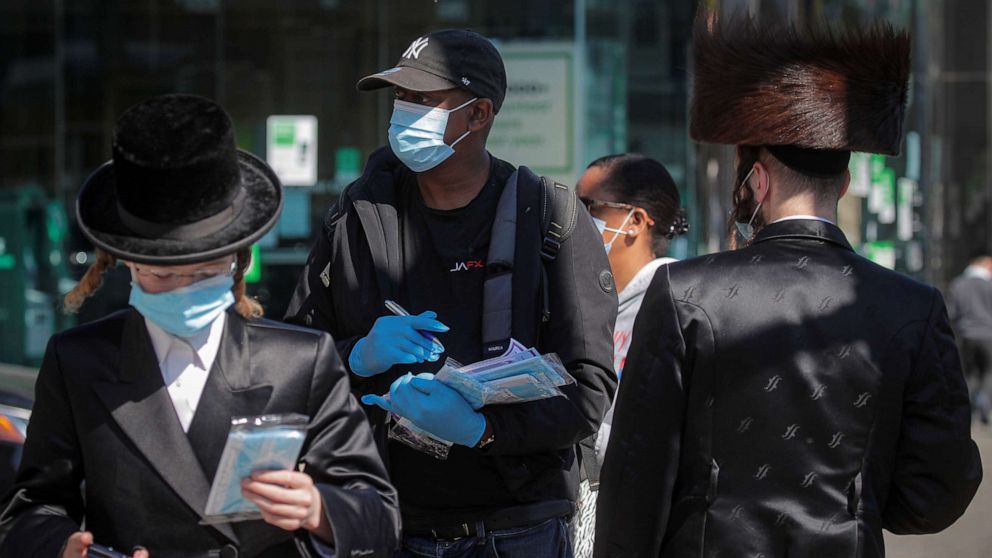 PHOTO: A member of New York City Test and Trace Corp. hands out masks to Ultra-Orthodox Jewish men during the outbreak of coronavirus disease in the Brooklyn borough of New York, Oct. 9, 2020.