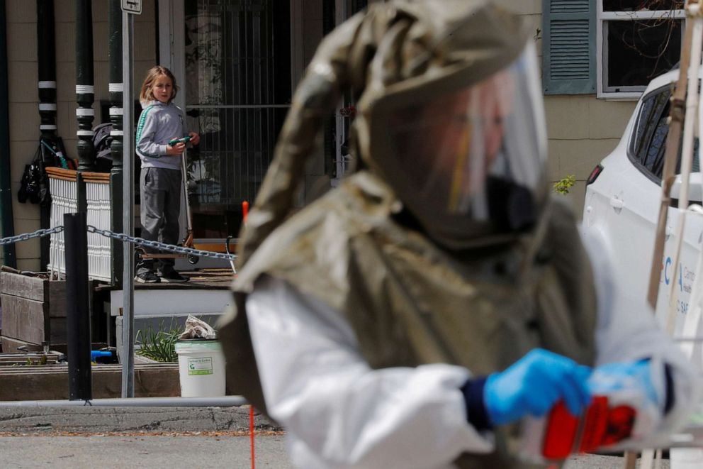 PHOTO: A child looks out from a front porch as a nurse practitioner takes a sample to be tested for the coronavirus disease at the CHA Somerville Hospital in Somerville, Mass., April 21, 2020.