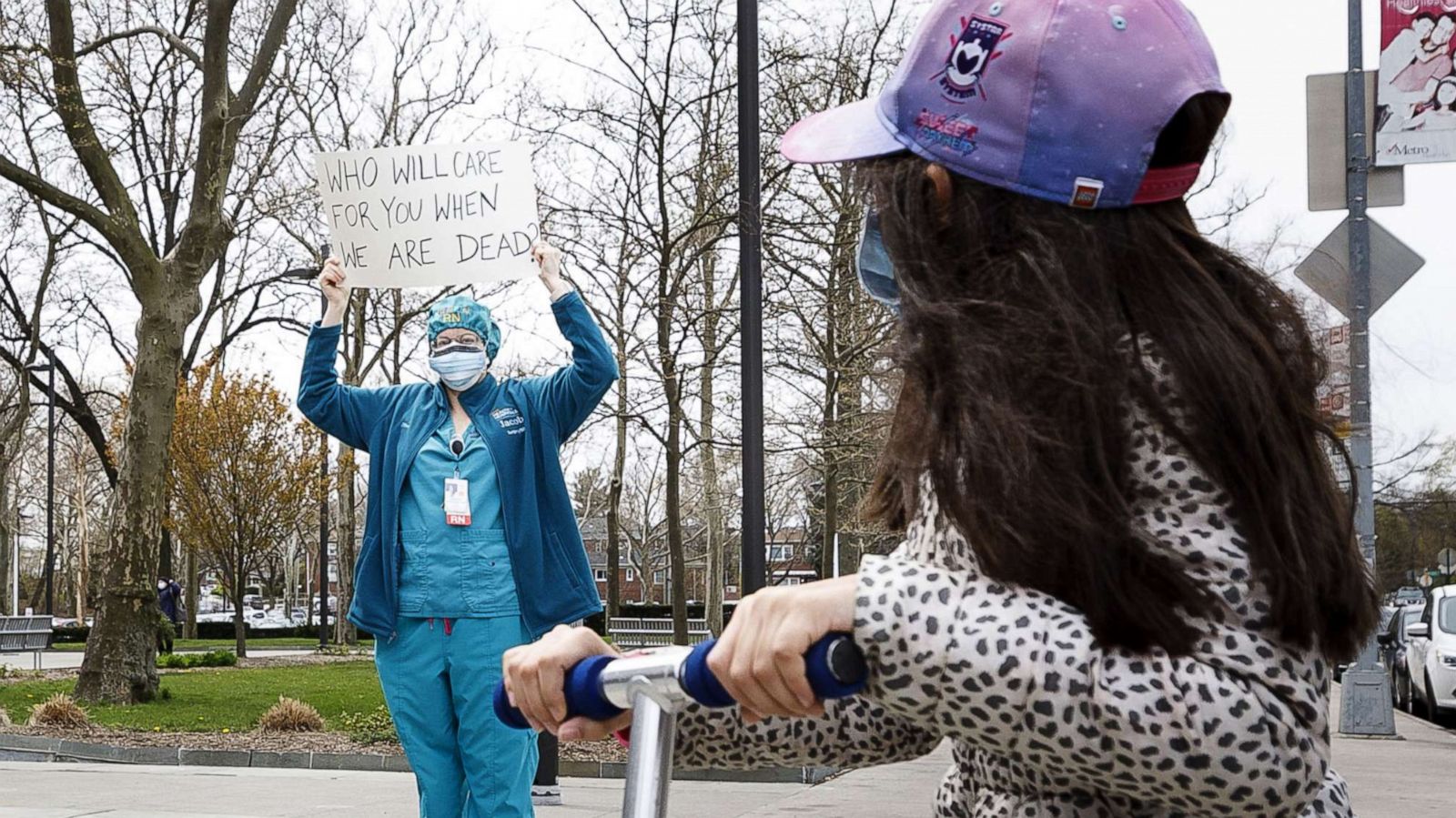 PHOTO: A child on a scooter looks at a nurse at Jacobi Medical Center participating in a rally to protest their lack of personal protective equipment, PPE, and institutional support in the Bronx borough of New York, April 17, 2020.