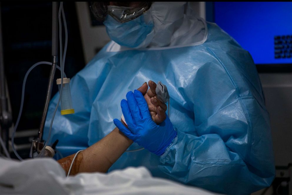 PHOTO: A doctor holds the hand of a COVID-19 patient in critical care in Barcelona's Hospital del Mar the Intensive Care Unit, Spain, Nov. 5, 2020.