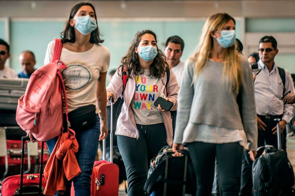 PHOTO: Passengers walk while wearing protective masks, as a preventive measure regarding the COVID-19 virus, at Jorge Chavez International Airport, in Lima, Feb. 27, 2020.