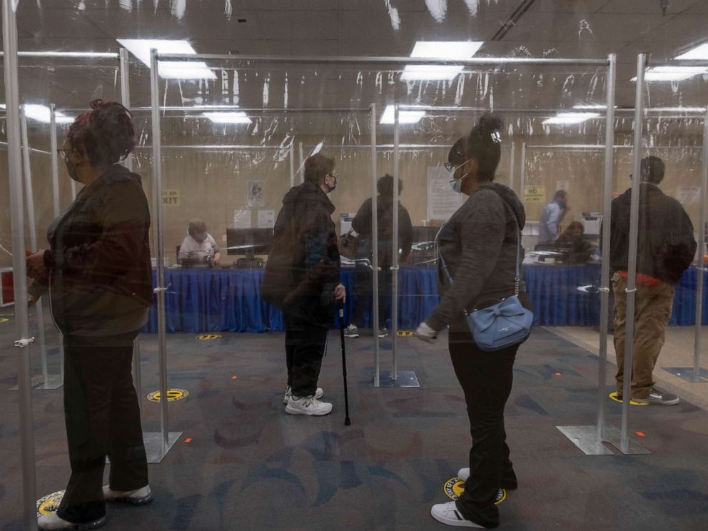 PHOTO: Ohio residents wait in line behind plastic barriers and stand six feet apart to help protect people from Coronavirus during early voting in Toledo, Oct. 6, 2020.