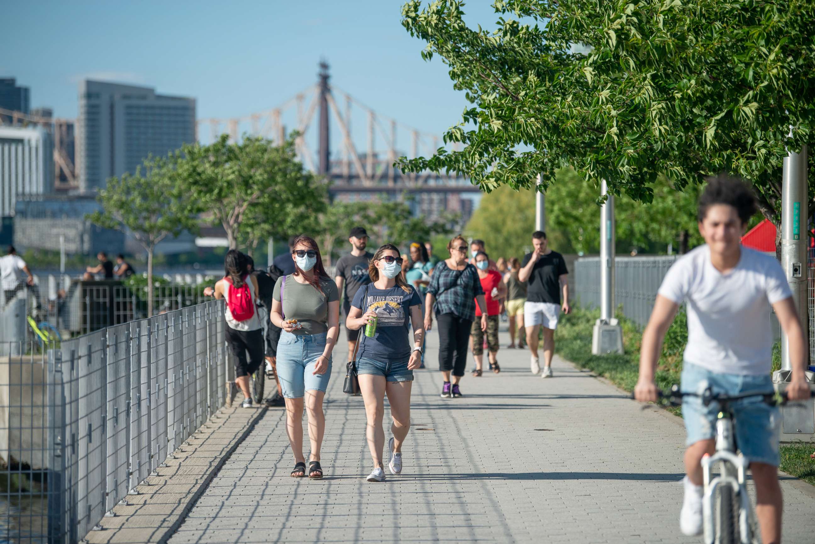 PHOTO: People wearing masks walk in Gantry Plaza State Park, Long Island City on May 30, 2020 in New York City.