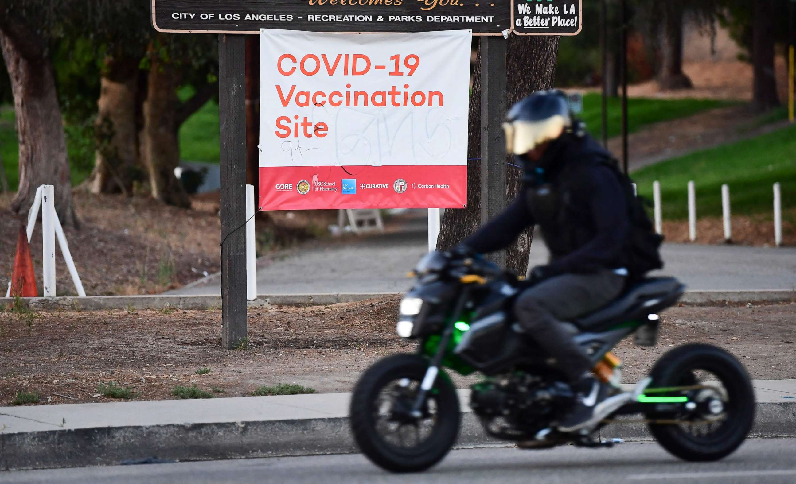 PHOTO: A motorcyclist rides past a COVID-19 vaccination site in Los Angeles, California, on July 6, 2021.