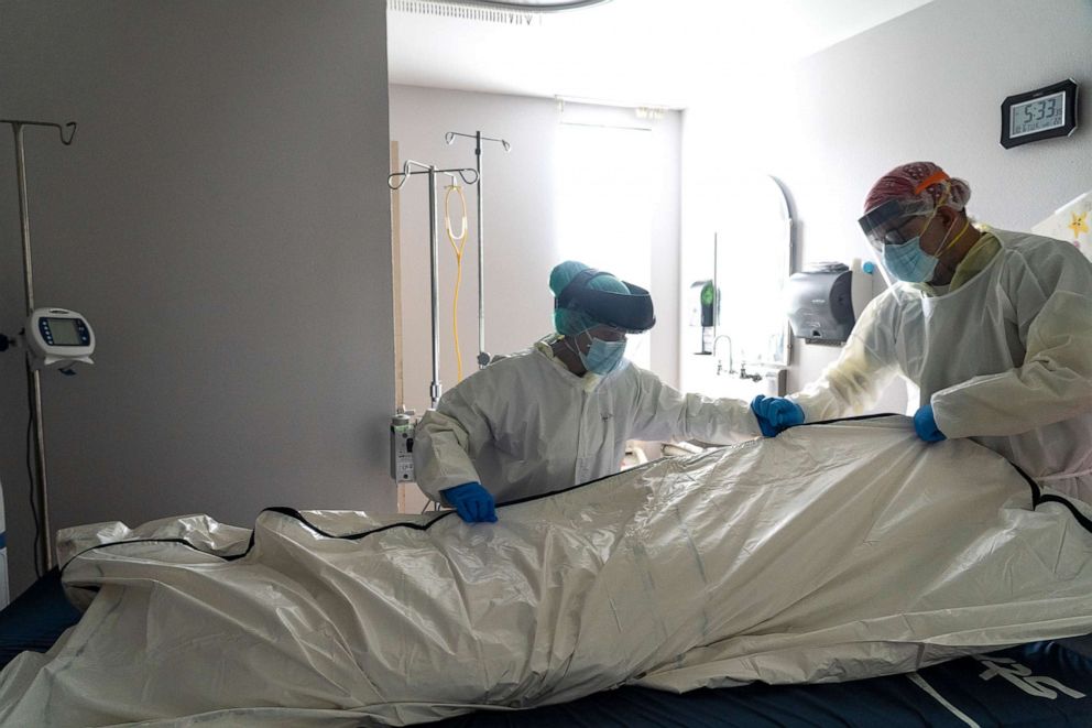 PHOTO: Medical staff wearing full PPE wrap a deceased patient with bed sheets and a body bag in the COVID-19 intensive care unit at the United Memorial Medical Center, June 30, 2020, in Houston.