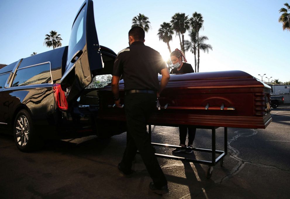 PHOTO: Funeral director Kristy Oliver (R) and funeral attendant Sam Deras load the casket of a person who died after contracting COVID-19 into a hearse at East County Mortuary, Jan. 15, 2021, in El Cajon, Calif.