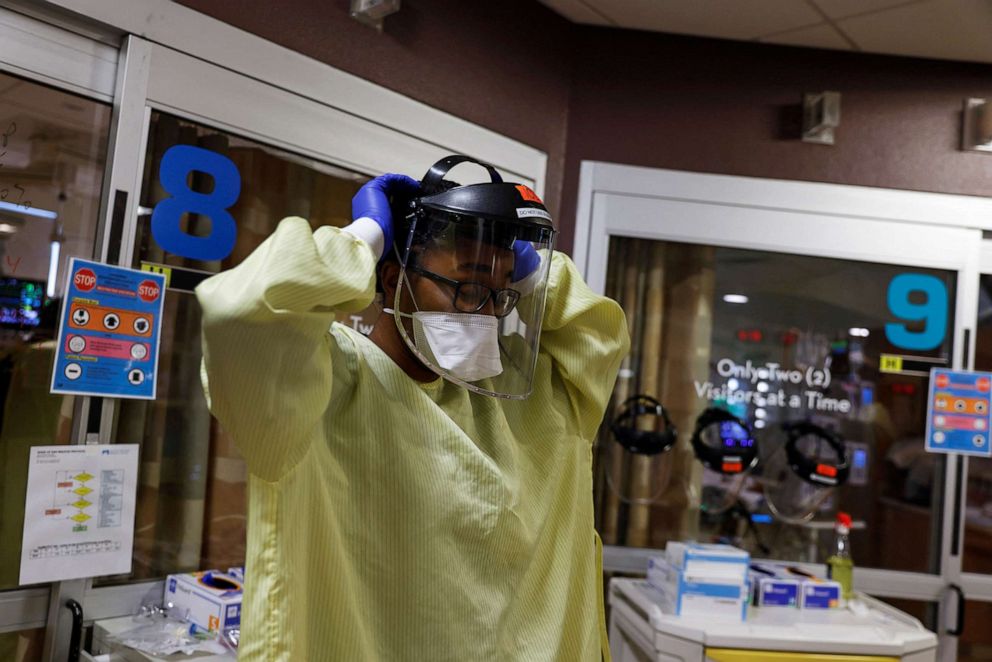 PHOTO: Kennedy Garcia, a Navy Lieutenant Junior Grade registered nurse, prepares her personal protective equipment gear before entering the isolation room of  a coronavirus disease COVID-19 patient in Farmington, N.M., Dec. 9, 2021. 