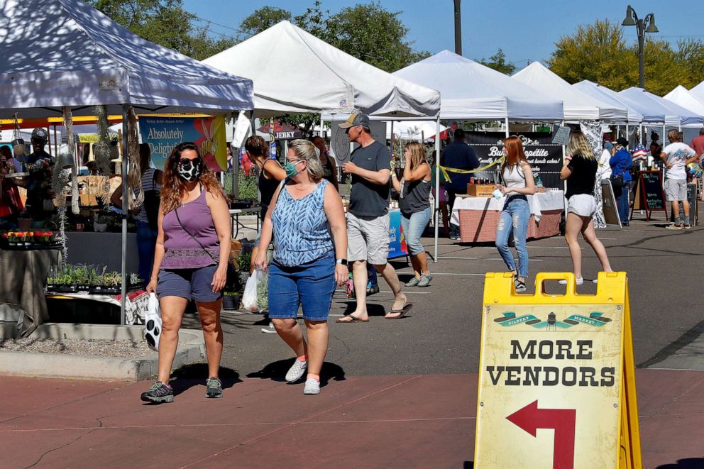 PHOTO: People wear masks to prevent the spread of coronavirus as they walk through the farmers market on April 25, 2020, in Gilbert, Ariz. 